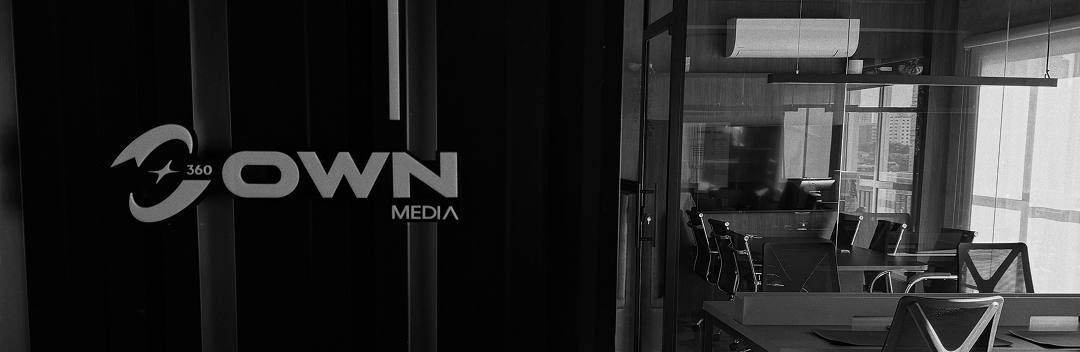 Letreiro OWN 360 MEDIA na parede da entrada, com o escritório da OWN ao fundo